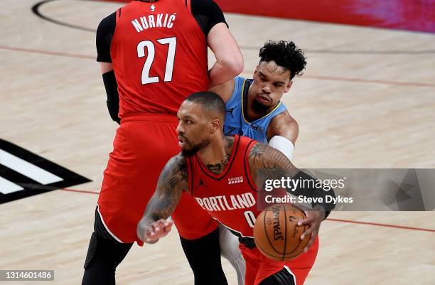 Damian Lillard of the Portland Trail Blazers dribbles the ball around a pick set by Enes Kanter as Dillon Brooks of the Memphis Grizzlies tries to...