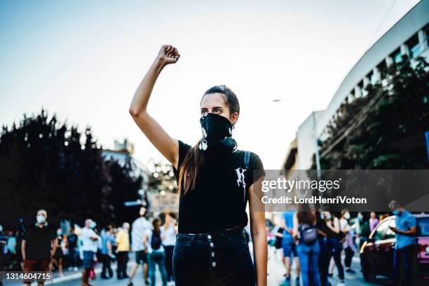 young woman protester raising her fist up - raised fist stock pictures, royalty-free photos & images