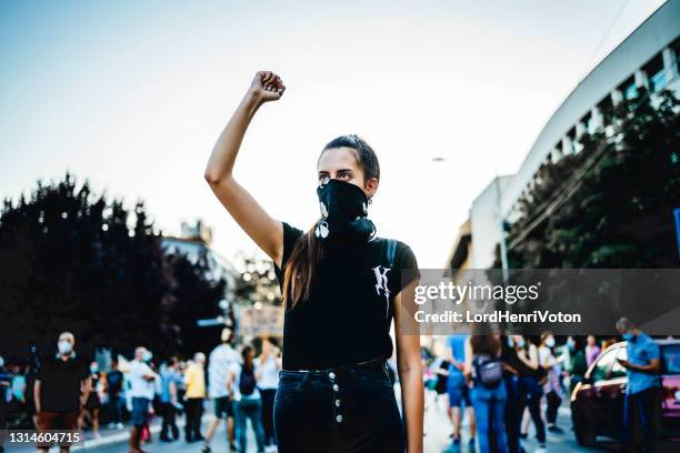 young woman protester raising her fist up - fist raised stock pictures, royalty-free photos & images