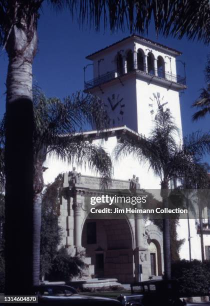35mm film photo shows the Santa Barbara County Courthouse with a clock tower above the entryway and palm trees lining the sidewalk, 1941.