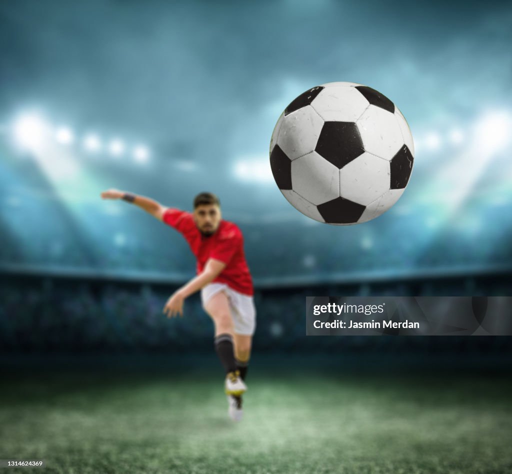 Soccer player kicking the ball at night stadium