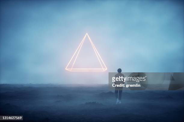 misterioso objeto en forma de pirámide y hombre caminando - pirámide fotografías e imágenes de stock