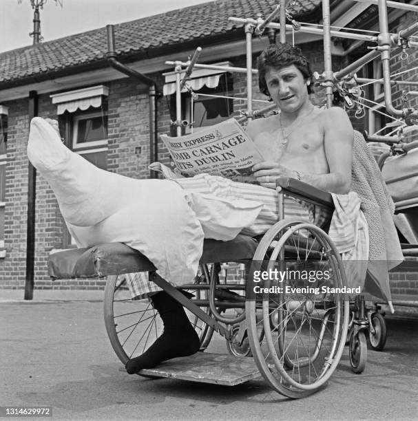 English footballer Roy McFarland of Derby County FC rests up with a leg injury, UK, May 1974. He is reading a copy of the Daily Express newspaper...