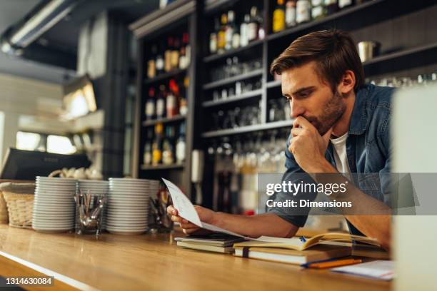 buchhalter schaut besorgt über die gewinn- und verlustbuchhaltung papiere - restaurant bill stock-fotos und bilder