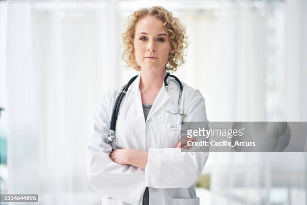 cropped portrait of an attractive young female doctor standing with her arms folded in the hospital - determination doctor stock pictures, royalty-free photos & images