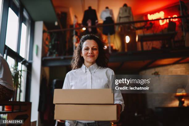 vrouwelijke eigenaar van een kledingwinkel die dingen voor levering voorbereidt - opening a box stockfoto's en -beelden