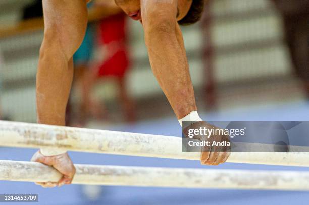 Gymnast of the French national team on parallel bars, one of the men's artistic gymnastics apparatus. Chalk to keep hands dry.