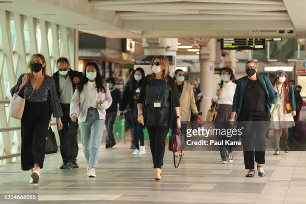 Pedestrians walk through a pedestrian overpass from the Perth train station wearing face masks on April 27, 2021 in Perth, Australia. Lockdown...