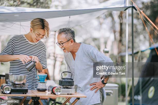 asian chinese teenage boy and father preparing dripping coffee for family at camping tent in afternoon - asian family camping stock pictures, royalty-free photos & images