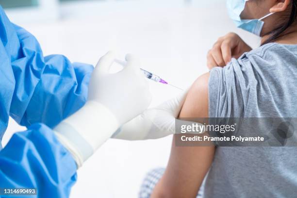 doctor making a vaccination in the shoulder of patient teens girls person, flu vaccination injection on arm, coronavirus,covid-19 vaccine disease preparing for human clinical trials vaccination shot - covid 19 vaccine stock pictures, royalty-free photos & images