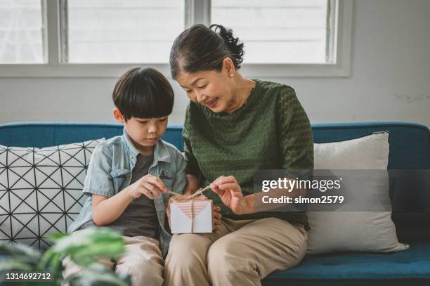 grand-mère et petit-fils excités déballant le cadeau d’anniversaire ensemble - cadeau danniversaire photos et images de collection