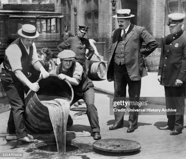 New York City Deputy Police Commissioner John A. Leach, right, watching Agents pour Liquor into Sewer following Raid during height of Prohibition,...