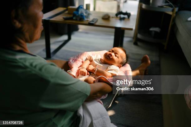 grandmother holding 1 month baby sunbathing at home for jaundice - examining newborn stock pictures, royalty-free photos & images