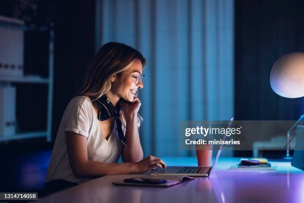 fröhliche dame mit kaffee und laptop in der nacht - neonfarben stock-fotos und bilder