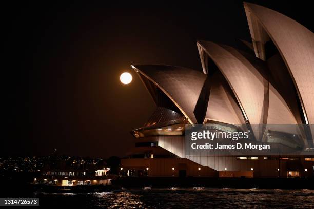 The moon rises behind the Sydney Opera House on April 27, 2021 in Sydney, Australia. The pink super moon is the first of two super moons which will...