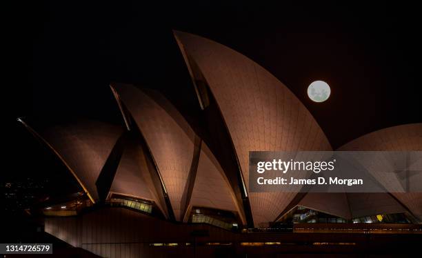 The moon rises behind the Sydney Opera House on April 27, 2021 in Sydney, Australia. The pink super moon is the first of two super moons which will...