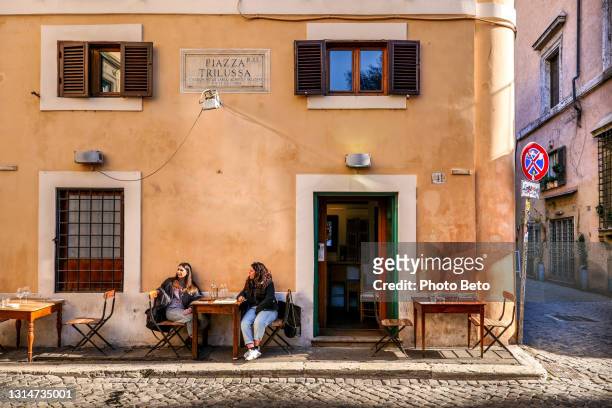 een paar vrienden genieten van het leven in een taverne in de oude wijk trastevere van rome - italiaanse etniciteit stockfoto's en -beelden