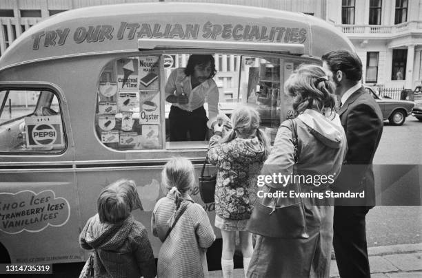 Children queuing at an ice cream van which is advertising 'Italian specialities', UK, 6th June 1974.