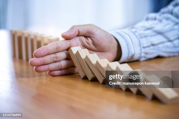 businessman stop domino effect. risk management and insurance concept - risikomanagement stock-fotos und bilder