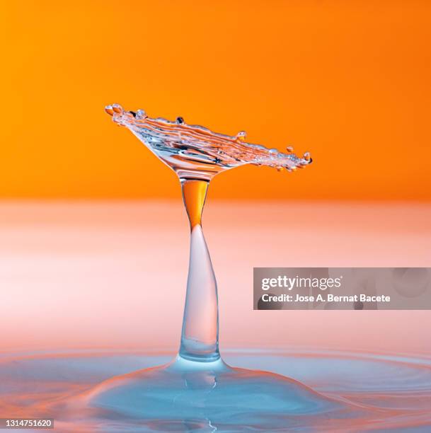 collision of water drops (water mushrooms), on a orange background - exploding glass stockfoto's en -beelden