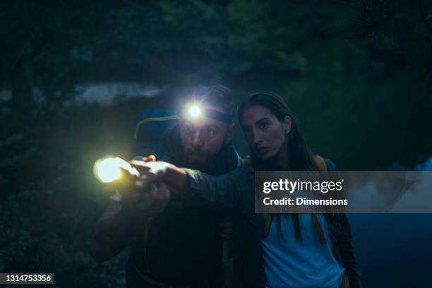 zwei wanderer mit taschenlampe wandern nachts im wald - flashlight stock-fotos und bilder