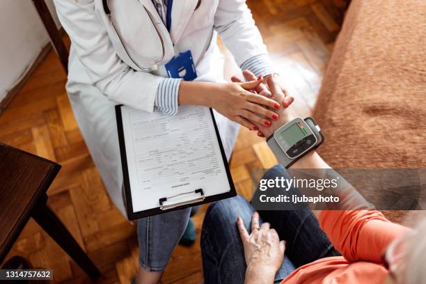 gesundheitsbesucherin und seniorin beim pflegeheimbesuch - hypertension stock-fotos und bilder