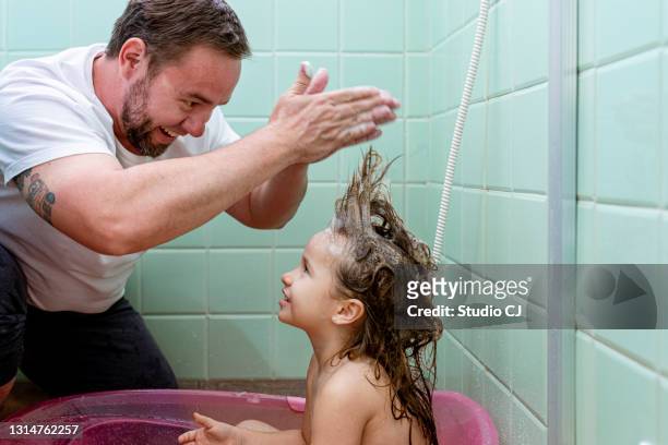 father playing with daughter's hair during bath. - girl hair stock pictures, royalty-free photos & images