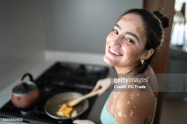 portrait of a young woman cooking at home - vitiligo stock pictures, royalty-free photos & images