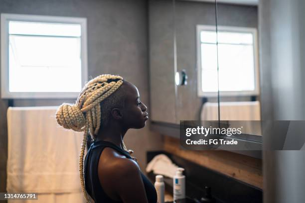 young woman looking in the mirror at home - standing mirror stock pictures, royalty-free photos & images