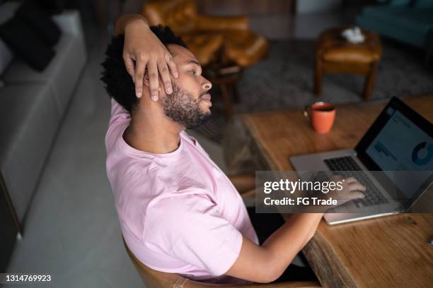 müde mann streckt sich während der arbeit zu hause - neck pain stock-fotos und bilder