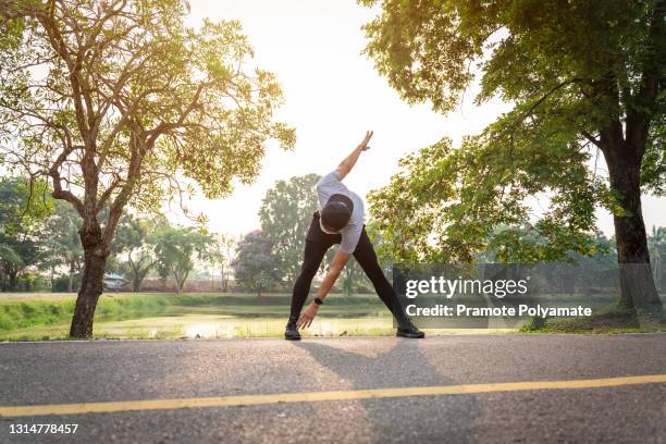 asian young man stretching in the park. warming up in morning. - hot body pic stock pictures, royalty-free photos & images