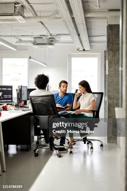 colleagues discussing in meeting at office - grupo pequeno de pessoas imagens e fotografias de stock