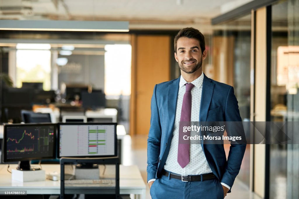 Happy Businessman With Hands In Pockets At Office