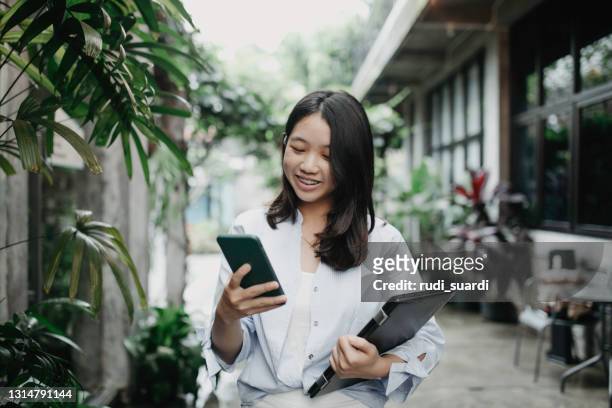 college student standing at entrance to university building - indonesia stock pictures, royalty-free photos & images
