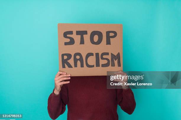 unrecognizable man holding a poster against racism - discrimination fotografías e imágenes de stock