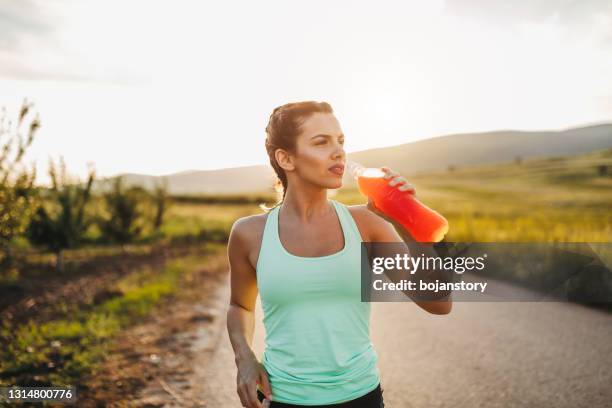 attraktive sportlerin ist erfrischend mit kaltem getränk nach hartem training - energydrink stock-fotos und bilder