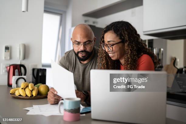 pareja haciendo finanzas domésticas juntos en casa - compito a casa fotografías e imágenes de stock