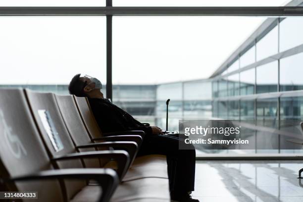 young man wearing protective face mask waiting for airplane - stornierung stock-fotos und bilder