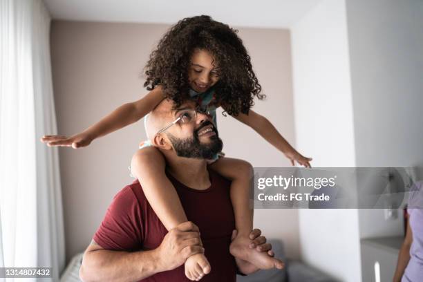 far som bär dotter på axlarna och leker med henne hemma - fathers day bildbanksfoton och bilder