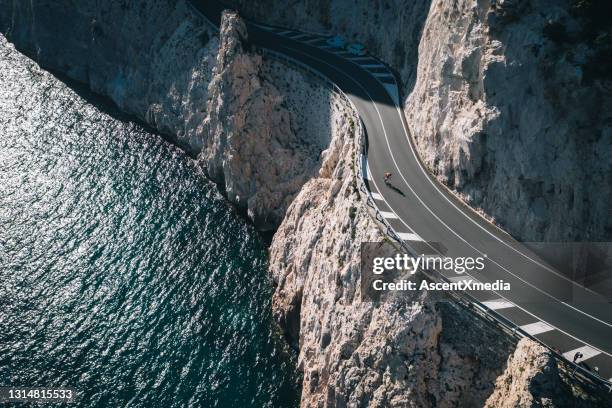 lucht mening van wegfietser die smalle, windende weg langs overzees berijdt - liguria stockfoto's en -beelden