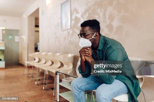 worried african american patient sitting in the waiting room at the hospital - covid anxiety stock pictures, royalty-free photos & images