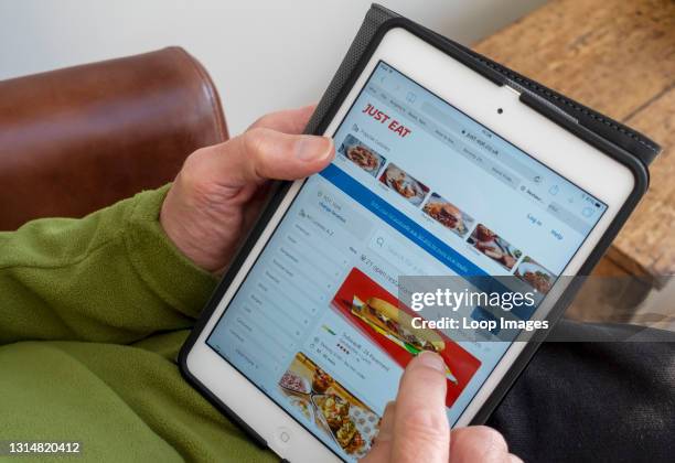 Close up of man looking at Just Eat website on tablet.