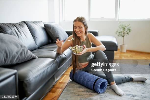 mooie vrouw die verse salade na intensieve huistraining eet - woman salad stockfoto's en -beelden