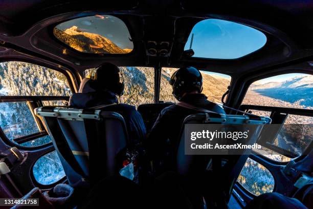 skiers fly in helicopter over snowcapped mountains - co pilot stock pictures, royalty-free photos & images