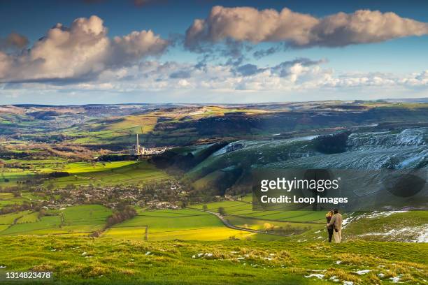 Couple look down the Hope Valley in Derbyshire from Mam Tor.