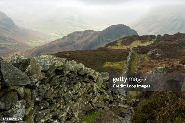 Footpath and dry stone wall on Lingmoor Fell with Side Pike beyond in the English Lake District National Park.