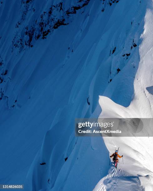 ski mountaineer climbs snowy mountain ridge crest - off piste stock pictures, royalty-free photos & images