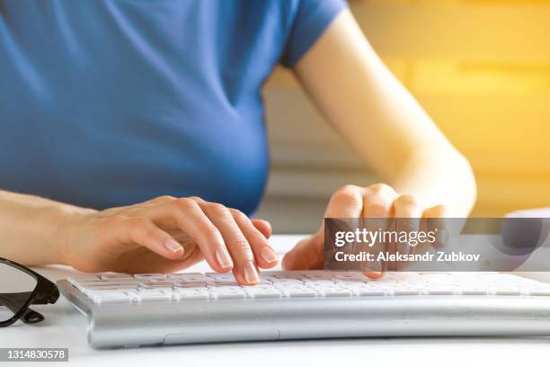 women's hands type text on the keyboard of a computer or laptop. an office worker at his desk. next to the computer mouse, notepad, glasses. the concept of business, freelancing, working at home. - siberian mouse fotografías e imágenes de stock