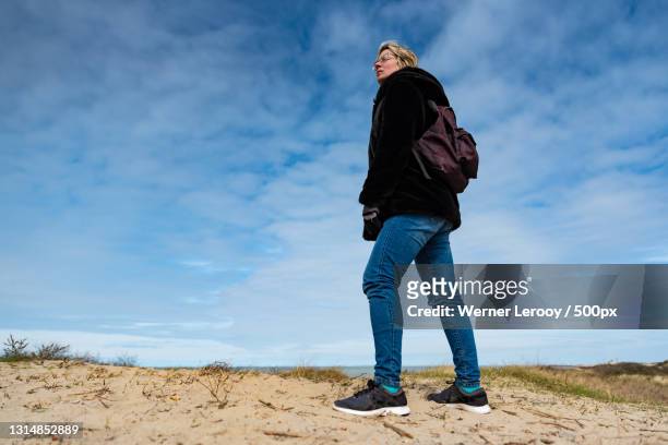 low angle view of man standing on sand against sky,het zwin,belgium - het zwin stockfoto's en -beelden