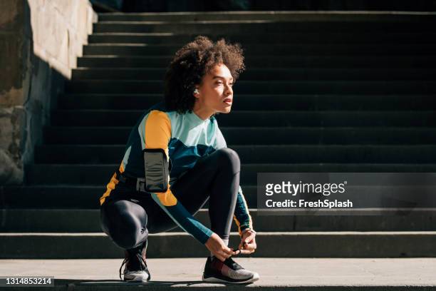 confident joven deportista atando su cordón de zapatos, agotado de un trote - cordón de zapato fotografías e imágenes de stock